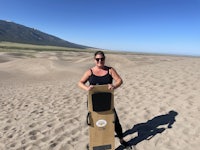 a woman standing in the sand holding a skateboard