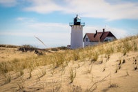 a lighthouse sits on top of a sand dune