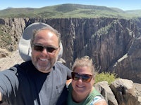 a man and woman taking a selfie in front of a cliff