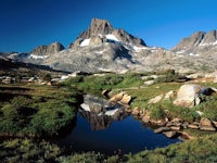 a mountain range is reflected in a small stream