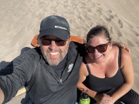 a man and woman laying on a sand dune